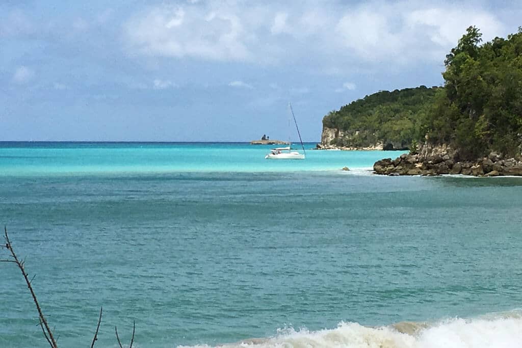 A sailboat at anchor in a turquoise cove in Marie-Galante